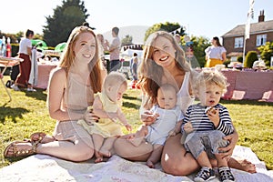 Portrait Of Two Mothers With Children On Rug At Summer Garden Fete