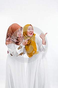 Portrait of two muslim woman. mother and daughter pointing right to copy space