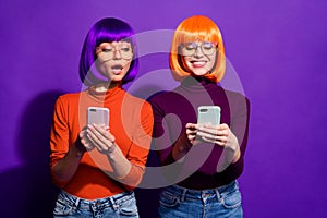Portrait of two nice attractive lovely cheerful cheery funny girls in wigs using device gadget reading sms message news