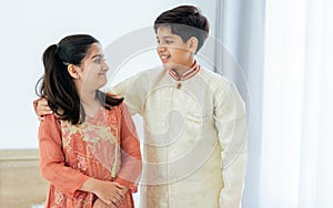 Portrait two people Indian siblings, brother, sister hugging with warmth, love, wearing traditional clothes, smiling with