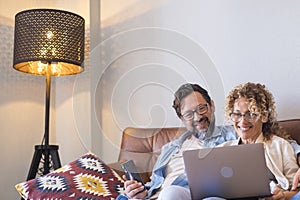 Portrait of two people man and woman enjoy technolofy connection toether with laptop and phone smiling and watching the computer photo