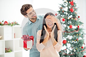 Portrait of two people shocked woman and her man give christmas gift package close eyes prepare x-mas surprise in house