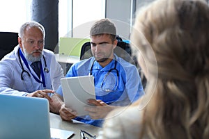 Portrait of two practitioners consulting patient in hospital