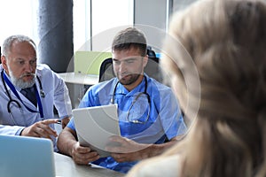 Portrait of two practitioners consulting patient in hospital