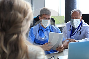 Portrait of two practitioners in face mask consulting patient in hospital