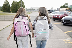 Portrait of two pre teenage girls studying outdoors in school yard left school