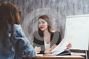 Portrait of two prett young women sitting at work desk. photo