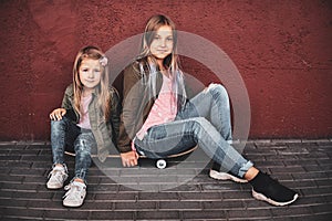 Portrait of two pretty sisters with skateboard