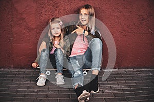 Portrait of two pretty sisters with skateboard