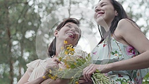 Portrait two pretty young girls in short dresses standing on rocky ground with wild flowers and looking forest enjoying