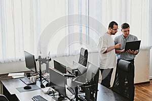 Portrait of two professional male programmers working on computer in diverse offices. Modern IT technologies