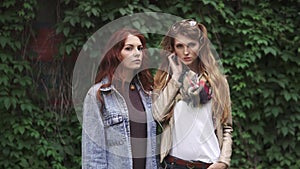 Portrait of two red-headed girls who listen to music in headphones. Beautiful girlfriends with freckles posing on camera