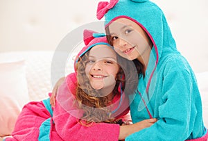 Portrait or two sister hugging each other and wearing bathtowels with hood