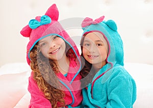 Portrait or two sister hugging each other and wearing bathtowels with hood