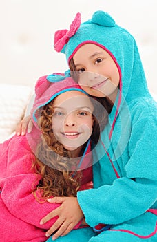 Portrait or two sister hugging each other and wearing bathtowels with hood