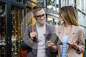 Portrait of two smiling business people walking and talking together in urban background