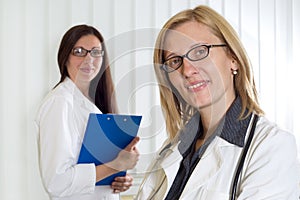 Portrait of Two Smiling Confident Female Doctors Looking at Camera Over White Background