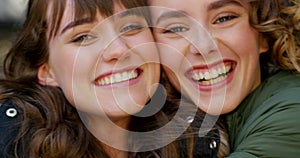 Portrait of two smiling friends hugging and looking happy outside. Faces of cute and cheerful best friends bonding and