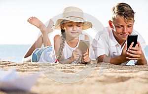 Smiling kids on beach with phone in hands