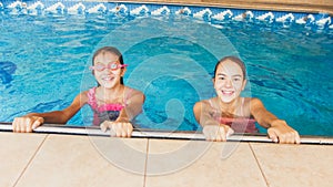 Portrait of two smiling teenage girls in swimming in pool. Family having fun and relaxing in water at summer holiday