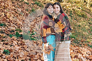 Portrait of a two smiling women outdoors in autumn park. Two beautiful girls friends in park. Couple of Women in Autumn