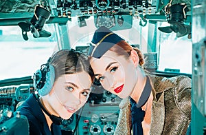 Portrait of two smiling women pilots. Beautiful Smiling Young Woman Pilot Sitting in Cabin of Modern Aircraft