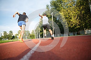 Portrait of two sportsmen competing on running track in park