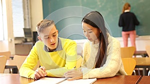 Portrait of two students sitting at desk in classroom, preparing together for college exam