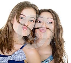 Portrait of a two teen girls have fun and make faces with moustache made of hair pigtail