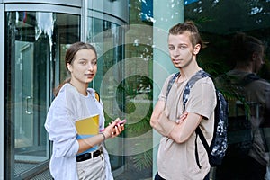Portrait of two teenage friends, guy and girl outdoor, educational building