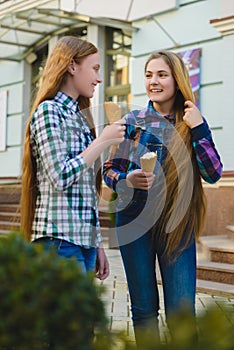 Portrait of two teenager girls standing together eating ice cream