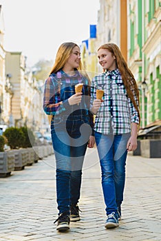 Portrait of two teenager girls standing together eating ice cream