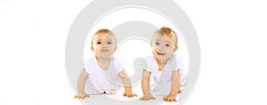 Portrait of two twin babies crawling and playing on white background