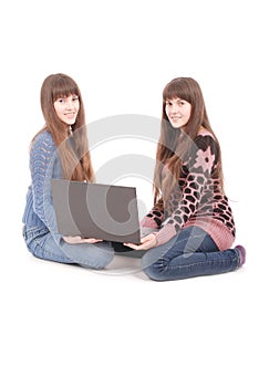 Portrait of two twins sisters with laptop