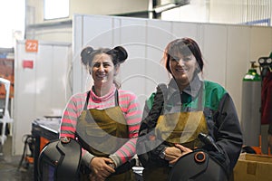 portrait of two welders holding welding masks in their hands and preparing for hard work in a factory