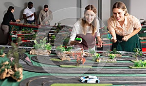 Portrait of two women playing with slot car racing track