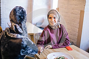 Two Muslim women in cafe, friends meeting