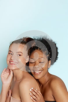 Portrait of two wonderful multiethnic women on blue background. Beautiful women, flawless skin. Diverse friends.
