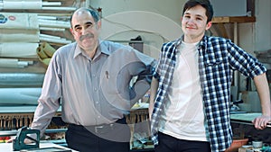 Portrait of two workers, standing in workshop, smiling and looking at camera