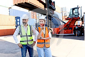 Portrait of two workers wearing safety vest and helmet discussing at logistic shipping cargo container yard, senior engineer man