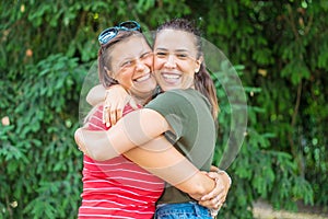 Portrait of two young beautiful lesbian smiling girls hug each other in a summer day whit colored t-shirt clothes and jeans