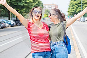 Portrait of two young beautiful lesbian smiling girls in a summer day whit colored t-shirt clothes and jeans