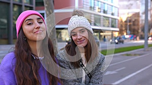 Portrait of two young beautiful women smile at camera on winter at city street