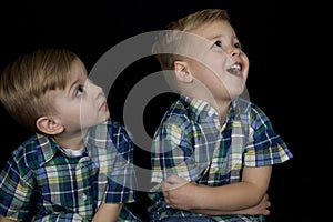 Portrait of two young boys matching shirts looking up away from