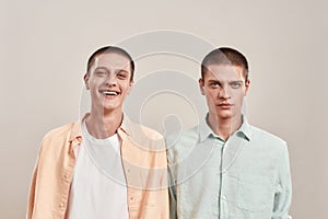 Portrait of two young caucasian men, twin brothers looking at camera with different face expressions while posing