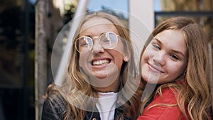 Portrait of two young caucasian women friends laughing happy at camera hugging each other enjoying relaxed lifestyle