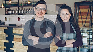 Portrait of two coffee house owners attractive young people standing inside coffee-shop, smiling and looking at camera