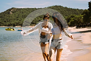 Portrait of two young female friends walking on sea shore happily