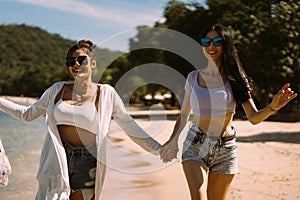 Portrait of two young female friends walking on sea shore happily