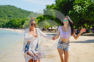 Portrait of two young female friends walking on sea shore happily